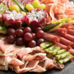 Frische gemischte Aufschnittplatte auf Schiefer mit Fruechten.